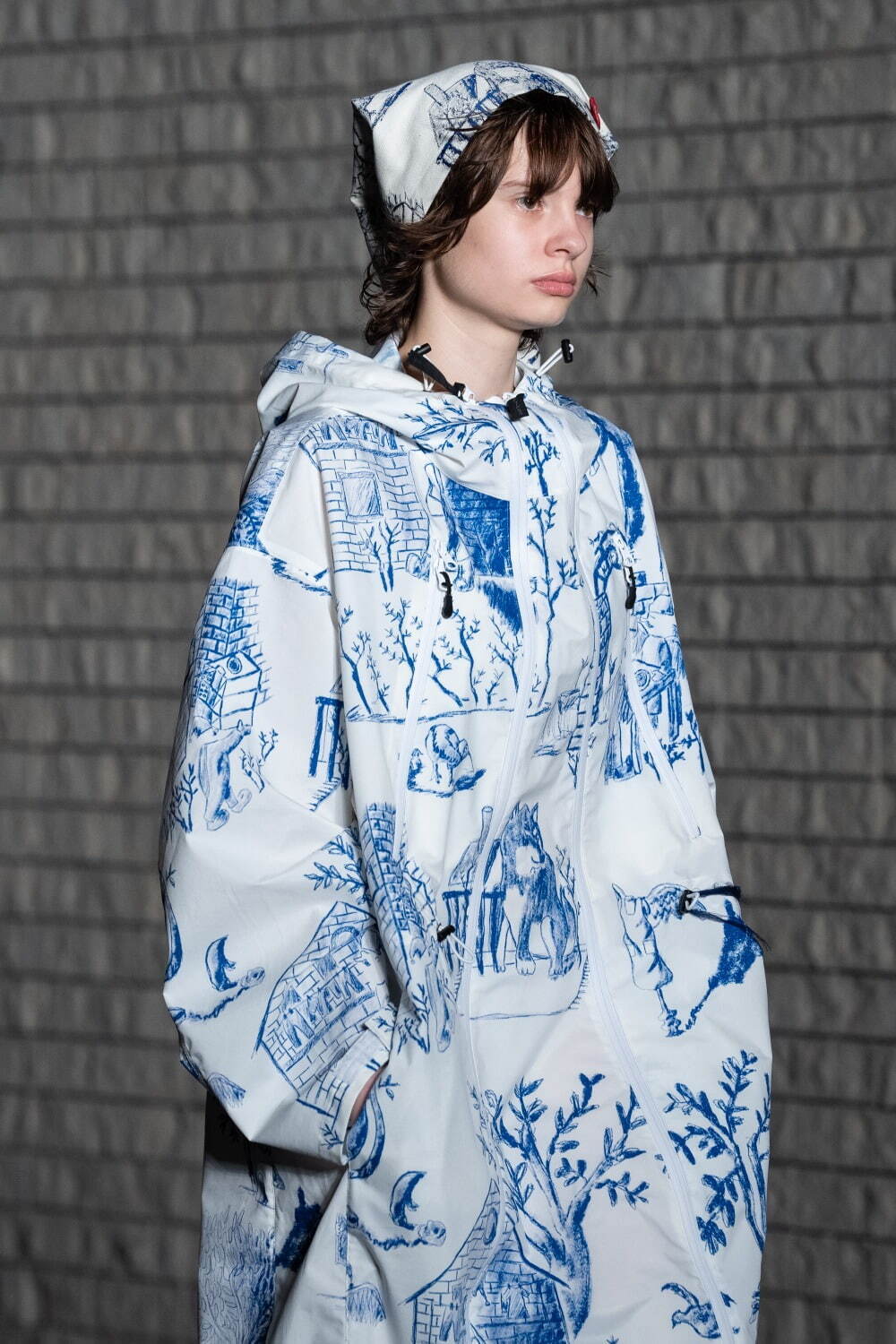 シンヤコヅカ×ワイルドシングスのフード付き防水コート、ブルーで描いた日常風景プリントを配して｜写真2